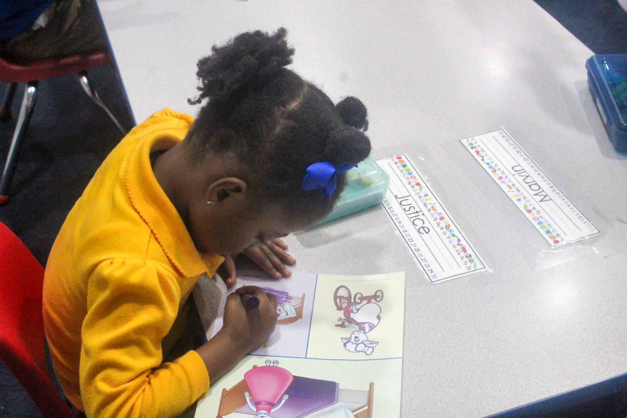 A child coloring at a classroom table